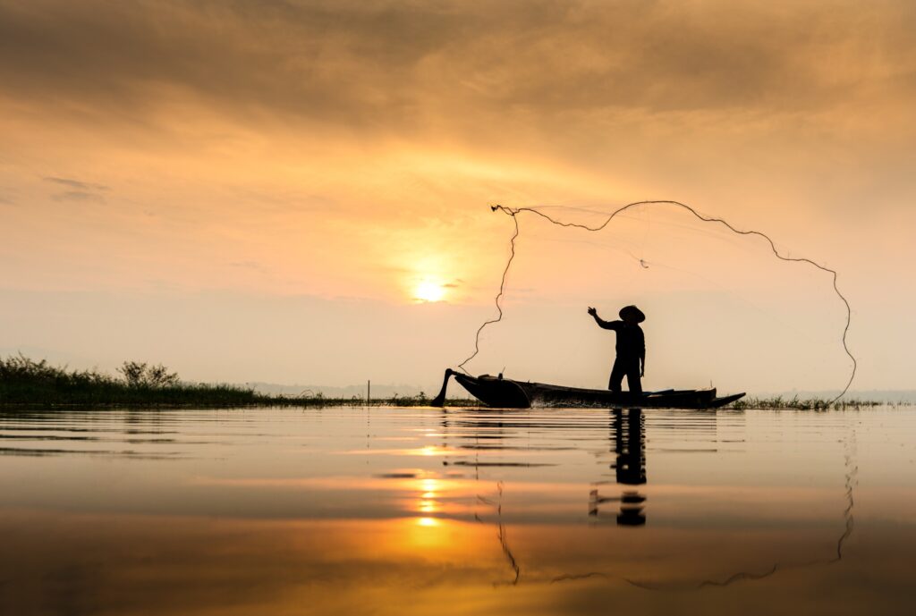 Thai,Fisherman,On,Wooden,Boat,Casting,A,Net,For,Catching